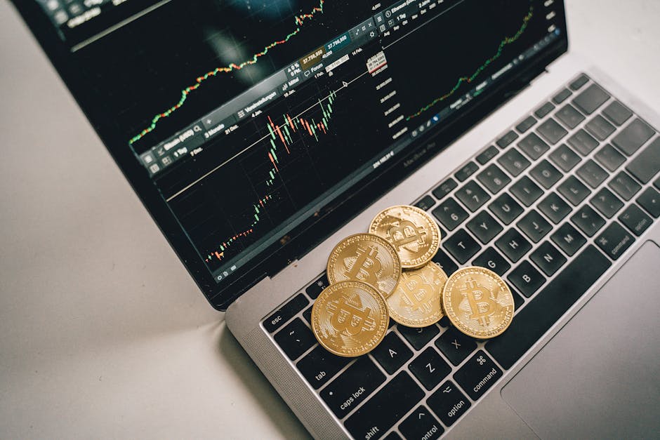 Golden bitcoin coins placed on a laptop keyboard with trading chart displayed on the screen